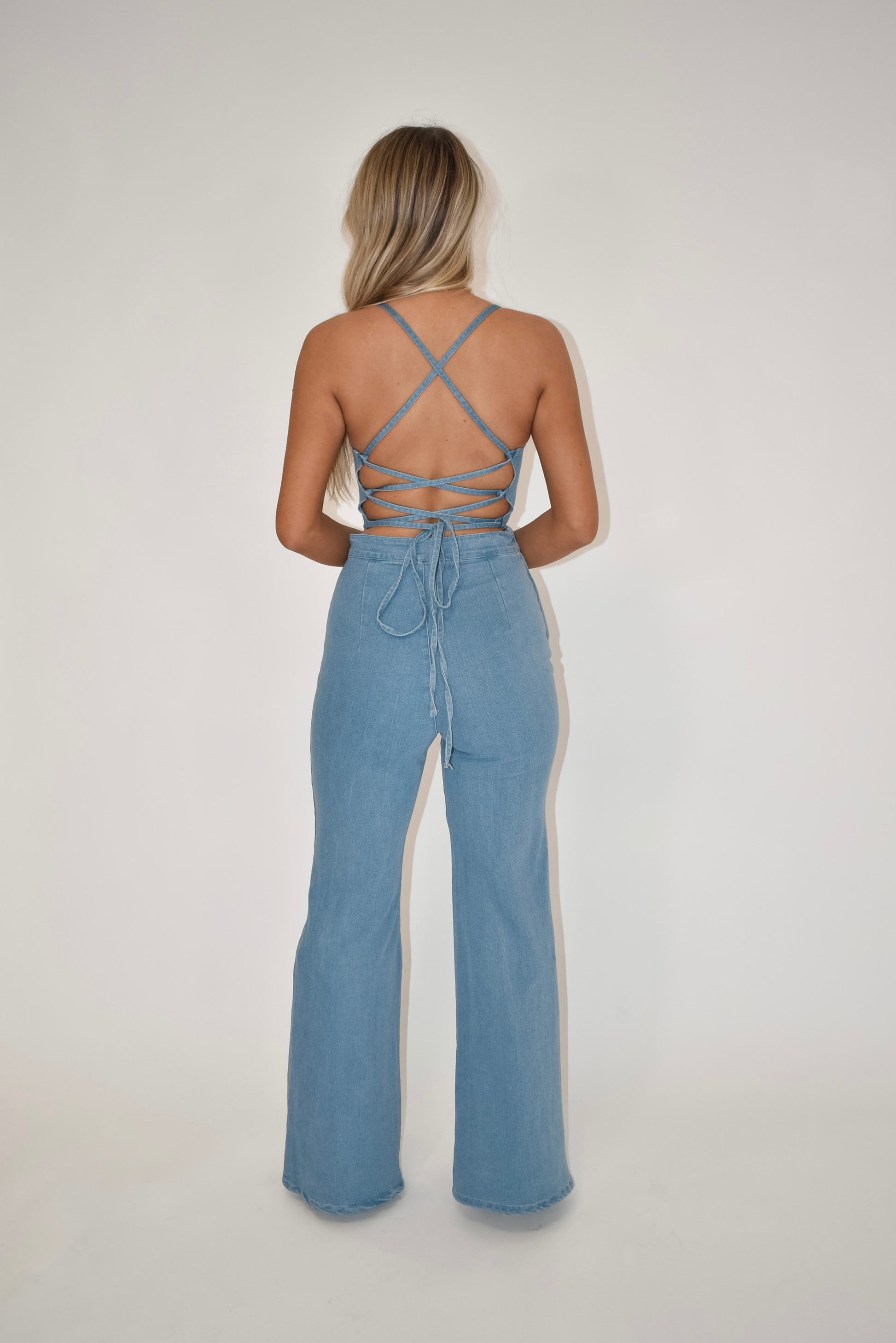 light was denim jumpsuit, open back jumpsuit, criss cross tie back jumpsuit, women's clothing boutique, online boutique, denim overalls,