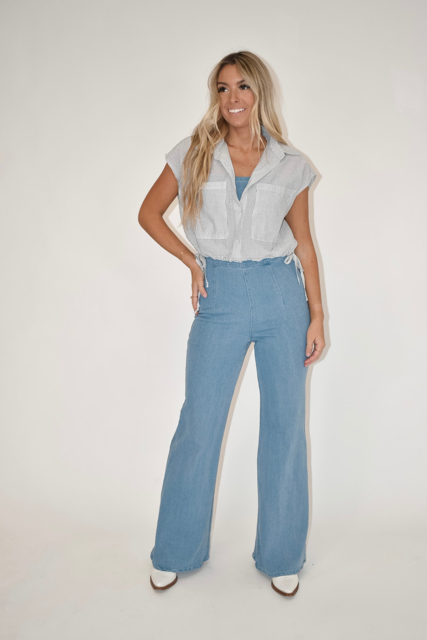 Women's clothing boutique, online women's clothing boutique, model is modeling the light wash denim jumpsuit with a stripe tank top over it, spring outfit, summer outfit 